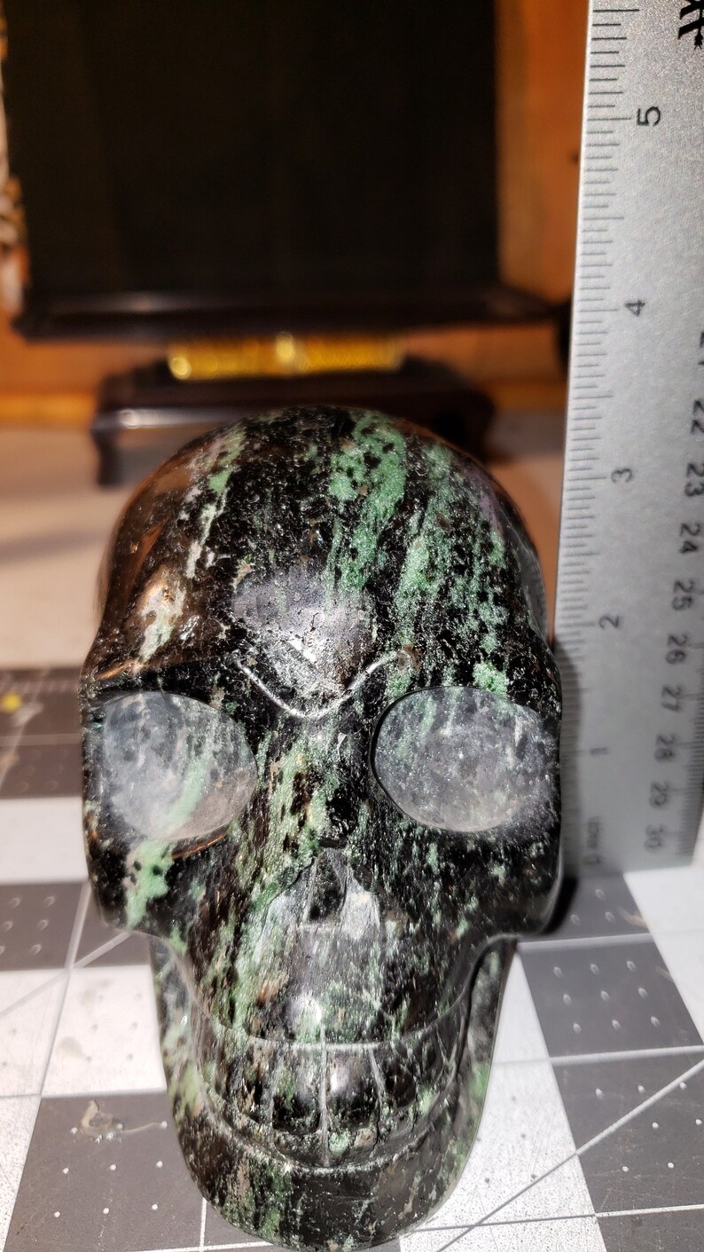 Puede incluir: Un cr&aacute;neo negro y verde hecho de piedra pulida. El cr&aacute;neo mide aproximadamente 5 cm de alto.