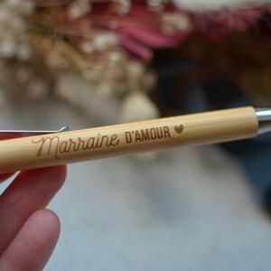 Op de afbeelding: Een houten pen met een zilveren clip en een zilveren punt. De pen is gegraveerd met de woorden "Marraine D'Amour" en een klein hartje.