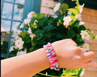 May include: A stack of colorful beaded bracelets with pink, red, white, and blue beads.