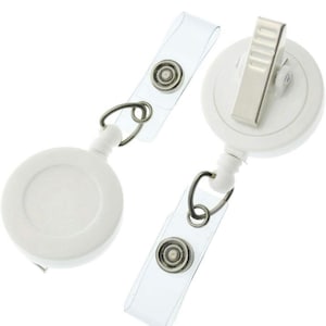 Pu&ograve; includere: Due portabadge retrattili bianchi con cinturini in plastica trasparente e bottoni a pressione in metallo. Ogni avvolgitore &egrave; dotato di una clip a coccodrillo girevole sul retro. Il testo Alligator (swivel) clip &egrave; stampato in basso nell'immagine.
