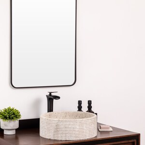 Round fluted marble vessel sink in light beige stone with polished interior