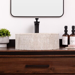 Round fluted marble vessel sink in light beige stone with polished interior