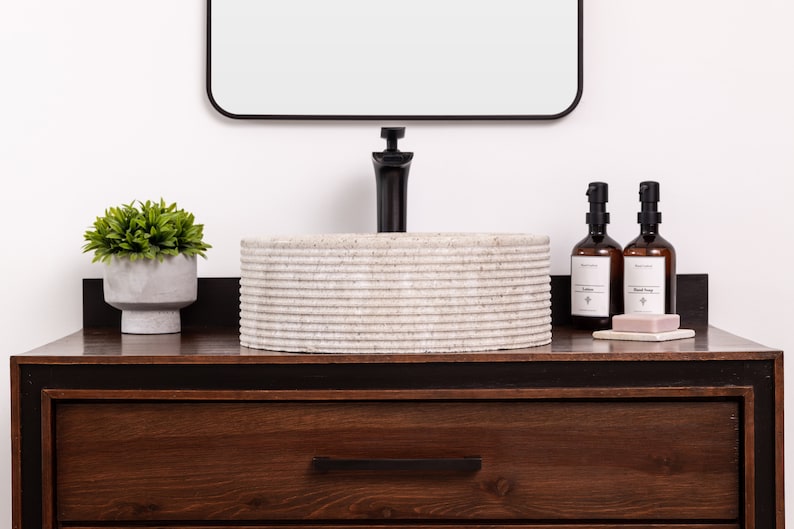 Round fluted marble vessel sink in light beige stone with polished interior