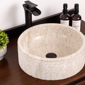 Round fluted marble vessel sink in light beige stone with polished interior