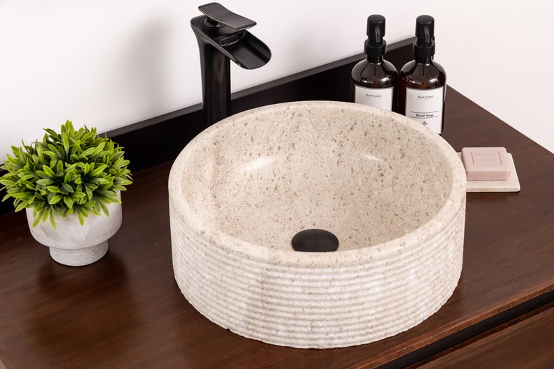 Round fluted marble vessel sink in light beige stone with polished interior