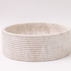 Round fluted marble vessel sink in light beige stone with polished interior