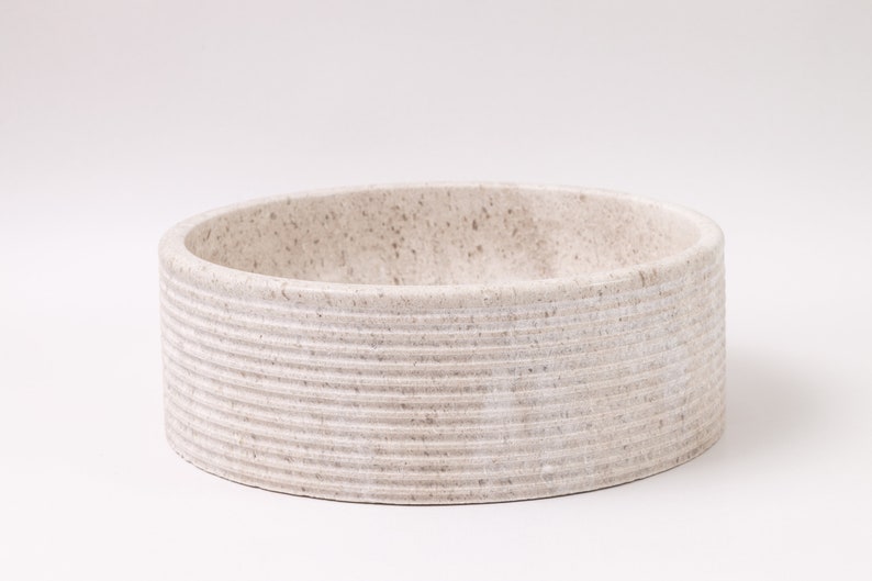 Round fluted marble vessel sink in light beige stone with polished interior
