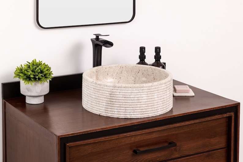 Round fluted marble vessel sink in light beige stone with polished interior
