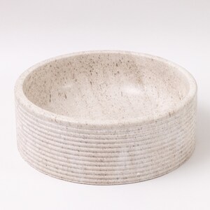 Round fluted marble vessel sink in light beige stone with polished interior