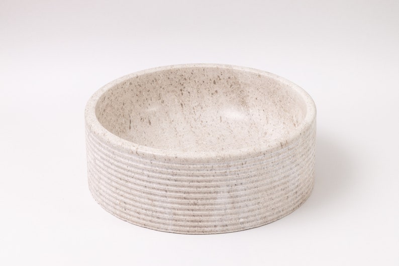 Round fluted marble vessel sink in light beige stone with polished interior