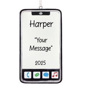 May include: A white smartphone-shaped ornament with a black border and a silver loop for hanging. The screen displays the name "Harper", the text "Your Message", and the year "2025". Icons for phone, email, chat, and music are at the bottom.