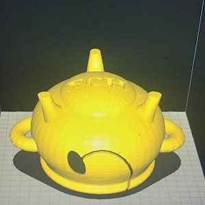 May include: A yellow 3D printed teapot with a rounded body and a spout. The teapot has a handle and a lid. The word "TEA" is printed on the side of the teapot.
