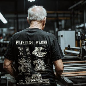 May include: A man wearing a black t-shirt with a white print of a printing press diagram and the text "PRINTING PRESS".