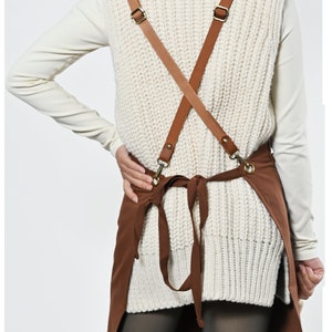 May include: Brown canvas apron with adjustable brown leather straps and a criss-cross back design.