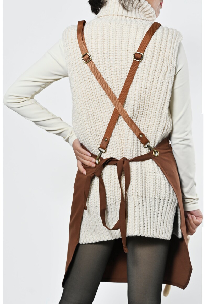 May include: Brown canvas apron with adjustable brown leather straps and a criss-cross back design.