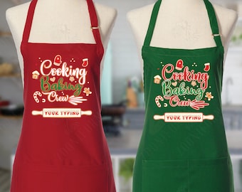Könnte beinhalten: Zwei Weihnachts-Schürzen, eine rote und eine grüne, mit dem Text "Cooking Baking Crew" und einem Platz für einen personalisierten Text.