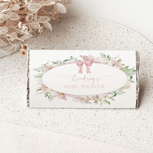 May include: A white chocolate bar wrapper with a floral design and the text "Lindsey's Baby Shower".