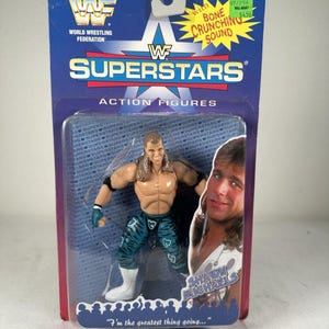 Può includere: Un action figure di Shawn Michaels della serie WWF Superstars nella confezione originale. Il personaggio ha lunghi capelli castani, polsini neri e pantaloni color verde acqua con motivi a cuore bianchi. La carta blu riporta il testo "with BONE CRUNCHING SOUND" e "I'm the greatest thing going..."
