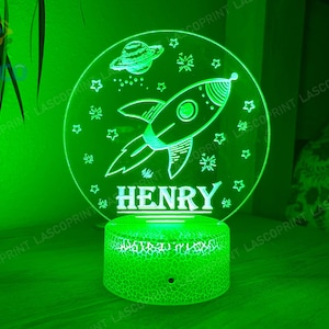 May include: Green night light with a rocket ship and stars design. The name "HENRY" is written below the rocket ship.