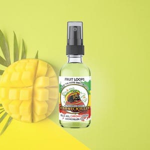 Puede incluir: Un frasco rociador de vidrio transparente con una tapa negra y una etiqueta que dice "Fruit Loops". La etiqueta presenta una imagen de dibujos animados de una persona con un sombrero y el texto "KronicKiller". Un mango en rodajas y hojas de palma están en el fondo.
