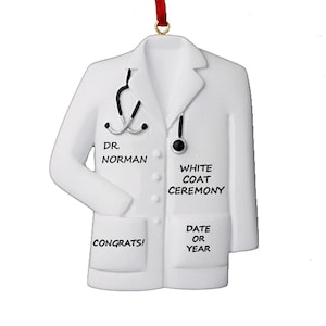 May include: White doctor's coat ornament with black text that reads "Dr. Norman", "White Coat Ceremony", "Congrats!" and "Date or Year".
