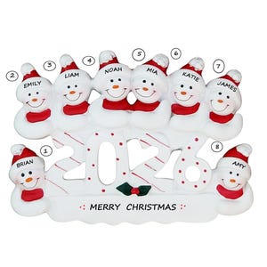 May include: A white snowman family ornament with eight snowmen wearing red scarves and hats. Each snowman has a name on its hat. The ornament has the year "2016" and the text "MERRY CHRISTMAS".