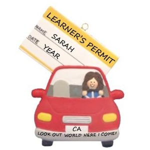 May include: A red car ornament with a learner's permit. The permit is yellow and white, with the name "SARAH" visible. The car has the text "LOOK OUT WORLD HERE I COME!" and "CA" on the front.