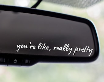 May include: A rearview mirror with the text "you're like, really pretty" written on it in white.