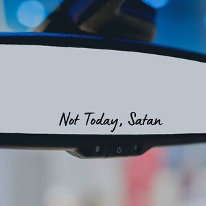 May include: A rearview mirror with the text "Not Today, Satan" written on it.