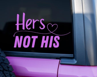 May include: A pink car with a black window sticker that says "Hers Not His" with a pink heart.