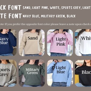 May include: Eight different colour crew neck sweatshirts with text on the front. The colours are navy blue, sand, light pink, white, sports grey, military green, light blue, and black. The text on the sweatshirts is in black or white font.
