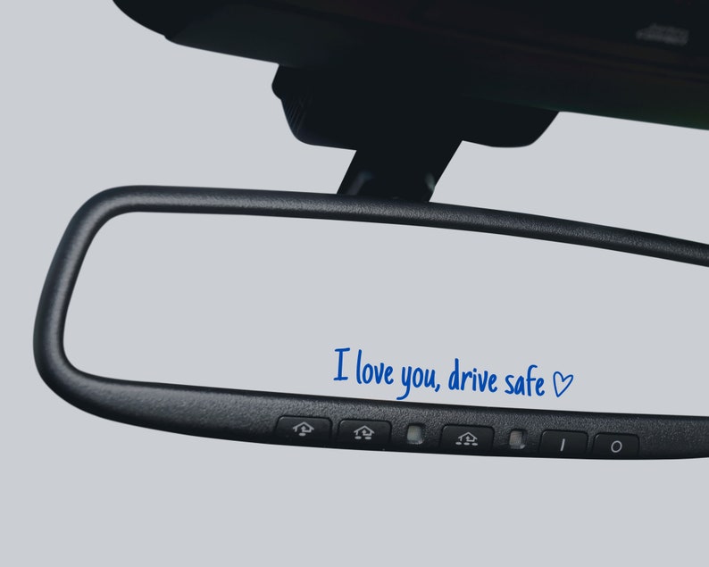 May include: A black rearview mirror with the message "I love you, drive safe" written in blue ink on the reflective surface.