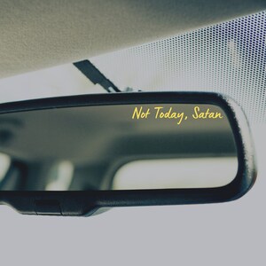 May include: A rearview mirror with the text "Not Today, Satan" written in yellow on the reflective surface.