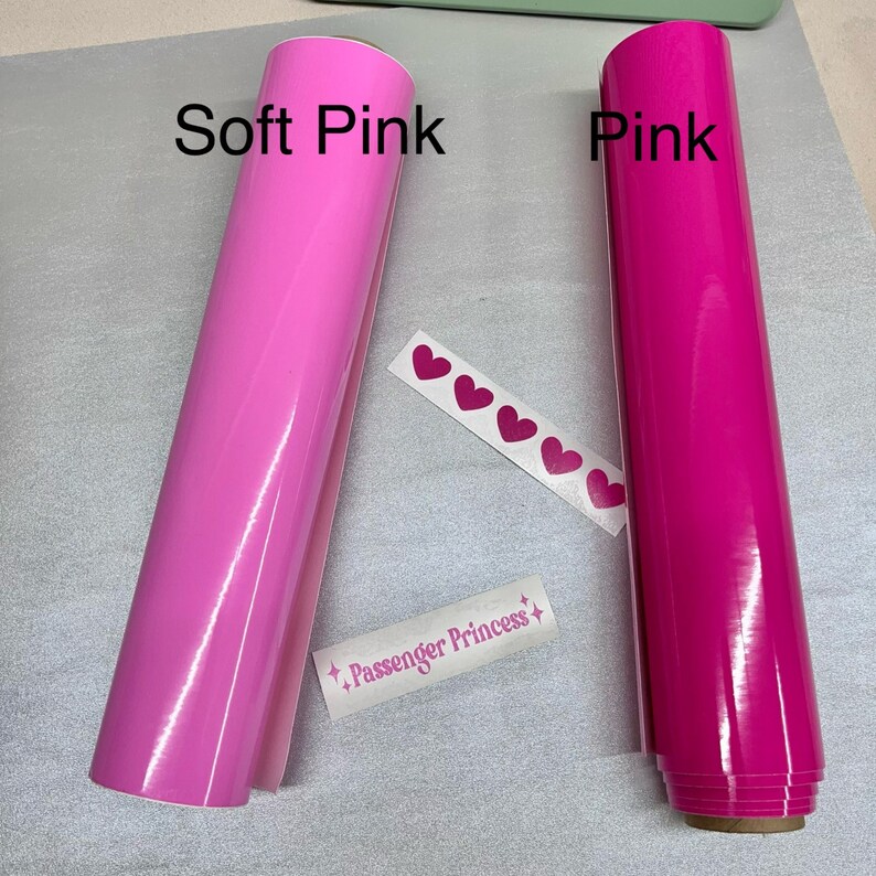 May include: Two rolls of vinyl adhesive film, one in soft pink and one in pink. The rolls are labeled "Soft Pink" and "Pink". The image also includes a sheet of pink heart stickers and a sticker that says "Passenger Princess".