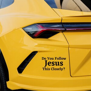 Puede incluir: Un coche amarillo con una pegatina negra en el parachoques que dice "Do You Follow Jesus This Closely?"