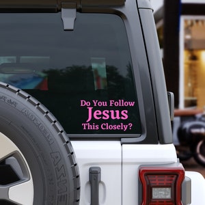 May include: A white car with a pink vinyl sticker on the back window that says "Do You Follow Jesus This Closely?"