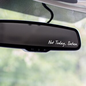May include: A black rearview mirror with a white sticker that says "Not Today, Satan".