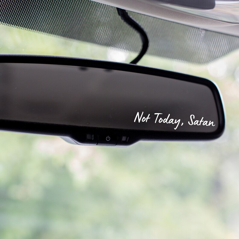 May include: A black rearview mirror with a white sticker that says "Not Today, Satan".