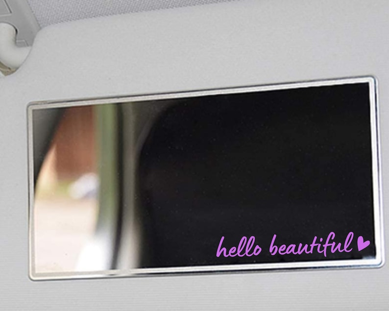 May include: A silver car visor mirror with a black background and the text "hello beautiful" in purple with a pink heart.