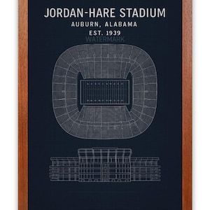 May include: A framed blueprint-style print of Jordan-Hare Stadium in Auburn, Alabama, established in 1939. The stadium is depicted in a top-down view and a side profile, with text at the top.