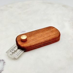 May include: A wooden razor blade holder with a gold knob. The blade is labeled "Falcon Platinum Stainless".