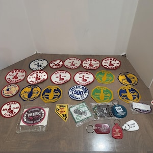 Könnte beinhalten: Eine Sammlung von Vintage-Bowling-Aufnähern und Schlüsselanhängern mit verschiedenen Designs, darunter Derby Fillies, KSWBA 500 Club und WIBC-Turnierauszeichnungen. Die Artikel zeigen Texte wie 1969, 1970, 1971, 1988 und St. Louis in 78 in Rot, Weiß, Blau und Gelb.