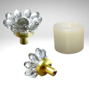May include: Two gold cabinet knobs with clear crystal flower accents. The knobs are shown on a white background.