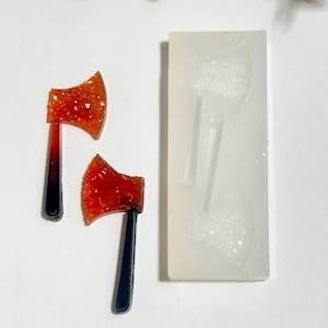 May include: Two red and black glitter axe charms with a clear silicone mold. The mold has two axe shapes.