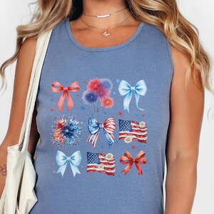 May include: A blue sleeveless tank top with a graphic print of red, white, and blue bows, fireworks, and American flags.