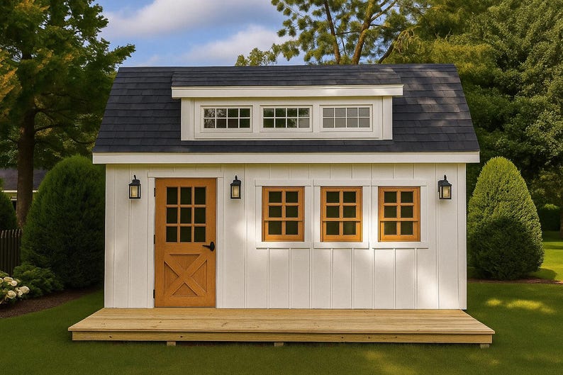 May include: A white shed with vertical siding, a dark gray shingled roof, and a wooden deck. It features a brown door with a window, three brown-framed windows, a dormer with three small windows, and three black outdoor wall-mounted lanterns.