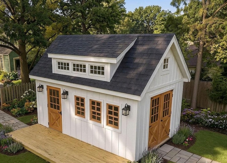 May include: A white shed with vertical siding, a dark gray shingled roof, and a dormer window. It features natural wood-toned doors with glass panes, multiple windows, and black exterior wall-mounted lanterns on the front and side walls.