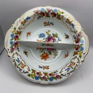 May include: A white porcelain divided serving dish with a gold rim and floral pattern. The dish has a scalloped edge and a handle on each side.