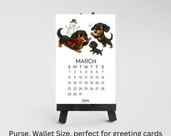 May include: A 2026 calendar card for March featuring an illustration of three black and tan dachshunds playing in the snow with a snowman. The text reads MARCH, the days of the week, the dates 1 through 31, and the year 2026. The card is on an easel.