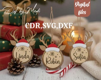 May include: Wooden Christmas ornaments shaped like reindeer with red Santa hats and the names "Linda", "Robin", and "Sofia". The ornaments are hanging from twine and are surrounded by gifts and pinecones. The text "Digital files" is visible.